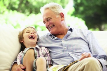 Grossvater lacht mit seinem Enkel im Arm.